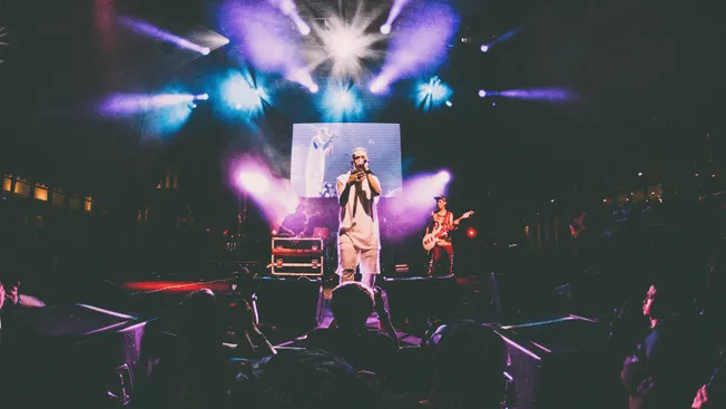 Concert performance at a live music event with stage lighting and band members playing guitars and singing on stage, showcasi