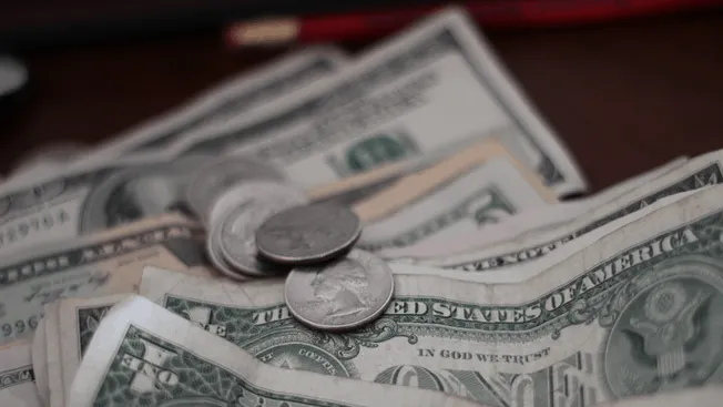 Stacks of US dollar bills and coins, representing earnings, revenue, or financial growth in the music industry and digital me