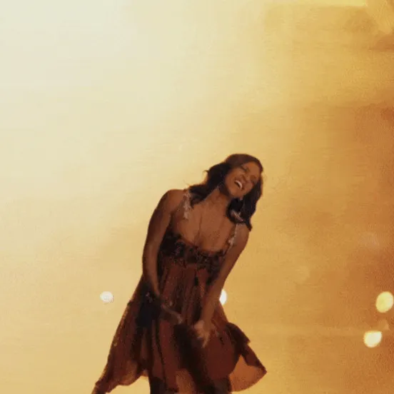 Shakira performing on stage with a joyful expression, highlighting her dynamic presence and musical talent at a live concert.