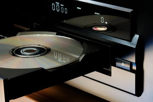 CD player with disc inserted, digital display showing track and output levels, modern music equipment for professional audio