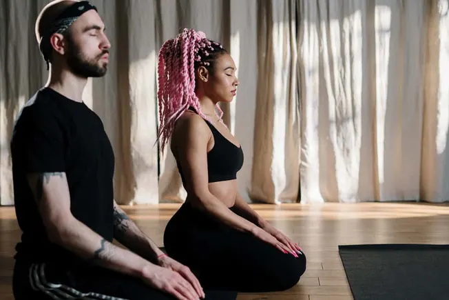 Meditating individuals practicing mindfulness and yoga in a peaceful indoor setting, focusing on mental clarity and relaxatio