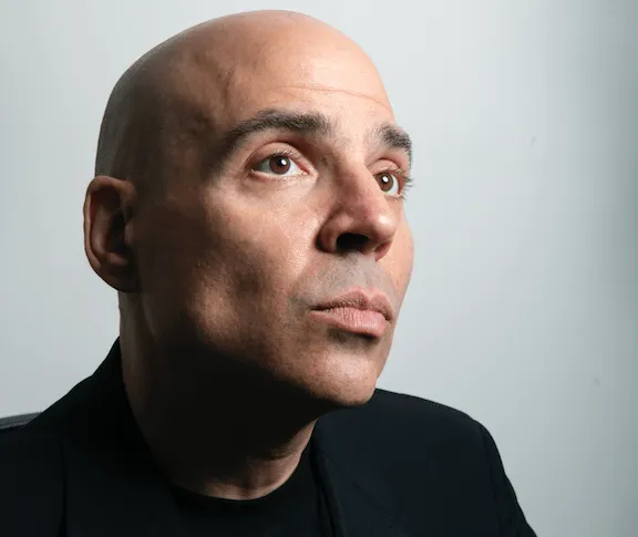 Bald man in black suit looking thoughtfully into the distance, studio portrait, neutral background, professional photography