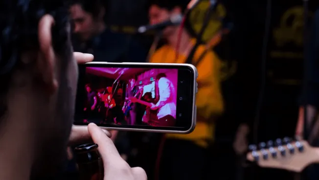 Concert photography of people recording live music performance on smartphone in a vibrant and energetic concert setting envir