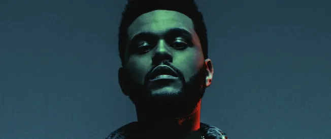 Bold male musician with a confident expression posing against a dark background with colorful lighting, emphasizing modernity