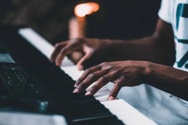 Hands playing digital piano, close-up shot, musician practicing piano, black keys, music composition, dark background, music