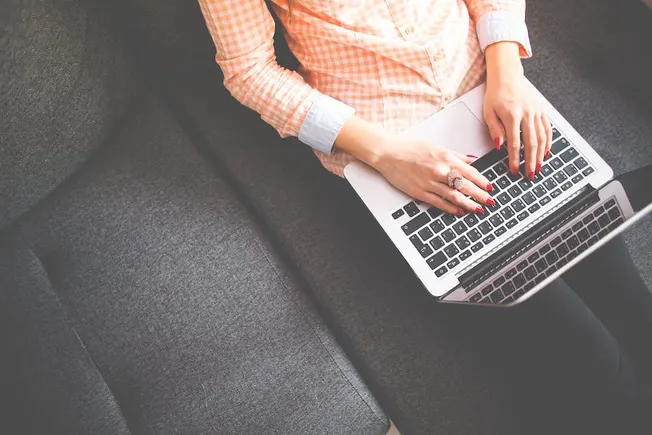 Laptop user working on a gray sofa, digital marketing, remote work, technology, cushions, casual home office, modern gadgets,