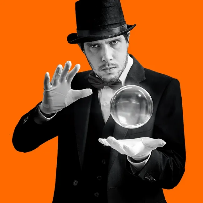 Mystical man in a tuxedo and top hat performing a crystal ball magic trick with an orange background.