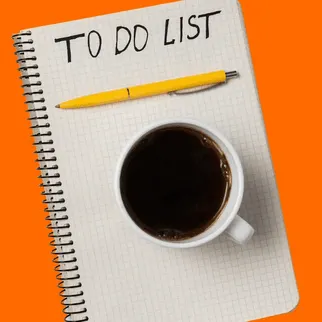 A notepad with "To Do List" written on it, a yellow pen, and a cup of coffee on an orange background.