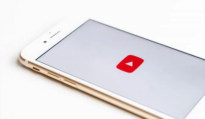 Mobile phone with YouTube app open, showcasing video content, representing digital media, online streaming, and content creat
