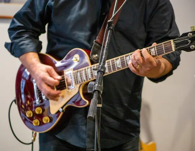 Guitarist playing electric guitar during a live performance, close-up on hands and instrument, ideal for music, band, live mu