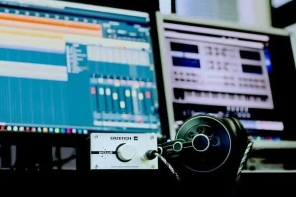 High-tech music production setup with computer monitors, mixing software, and audio equipment for digital music creation and
