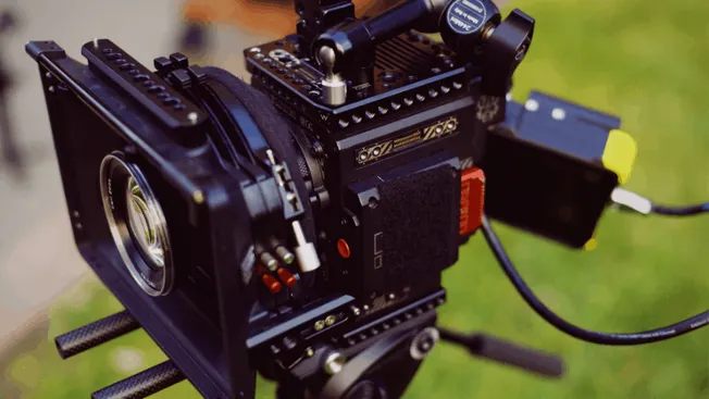 Professional cinematic camera setup for film production with accessories and mounting rig, outdoors on grass background.
