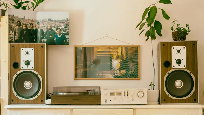 Vintage stereo speakers with a turntable and framed artwork in a cozy home setting, showcasing retro audio equipment and styl