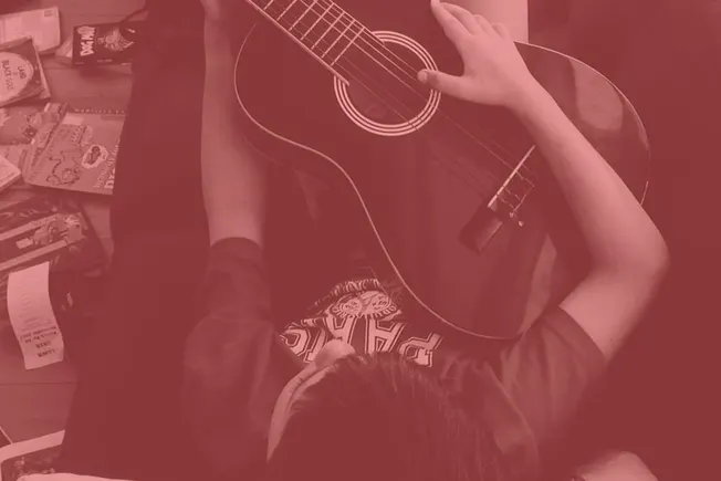 Acoustic guitar player practicing music at home, surrounded by music books and supplies, creating a cozy and artistic musical