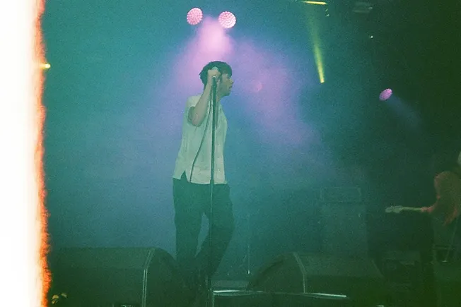 Male singer performing at a concert with colorful stage lights.