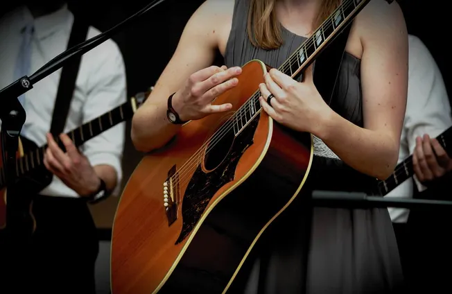 Guitarist playing acoustic guitar during live music performance at an event, focus on hands and instrument, musical performan