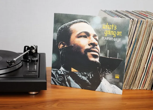 Close-up of a vintage vinyl record player next to a 1970s jazz album cover titled "What's Going On" by Marvin Gaye, with a st