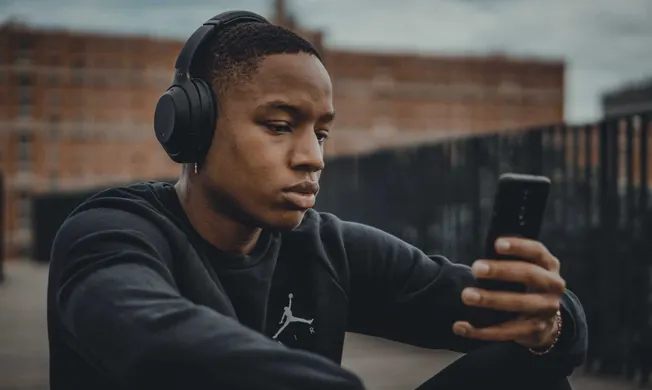 Listening to music with headphones outdoors on a city rooftop.