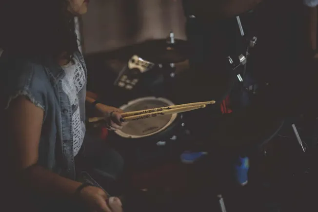 Drummer practicing with drumsticks on a drum kit, practicing percussion instruments in a music studio, indie music scene, you