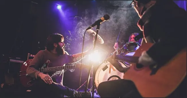 Guitarists performing live on stage during concert, musical instruments, stage lighting, indie music performance, musician ar