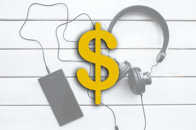 $ dollar sign with headphones and portable speaker on white wooden background, representing music monetization, digital music