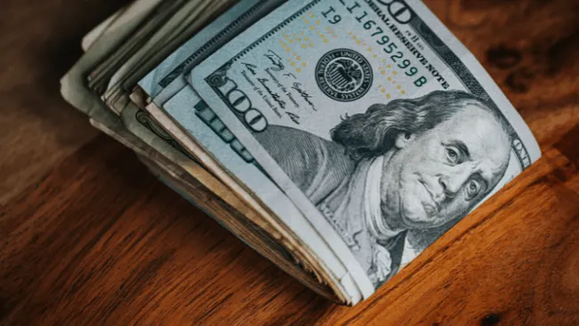 Bundles of US dollar bills stacked on a wooden surface, illustrating financial discussions or cash management.