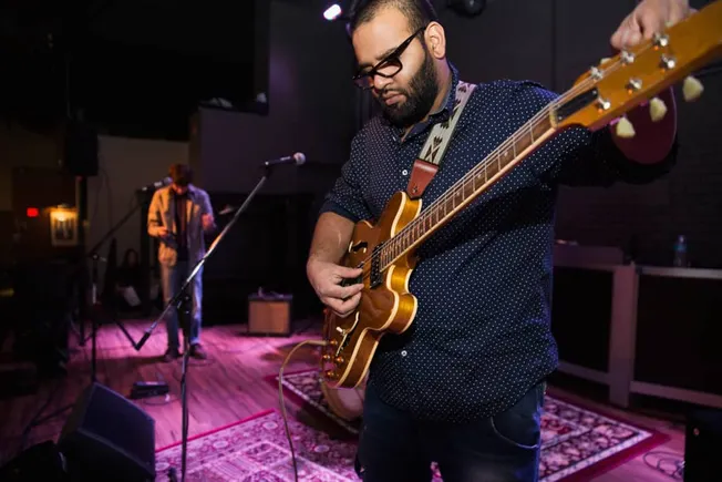Guitarist performing live on stage at a music venue, capturing a moment of musical expression with professional audio and sta