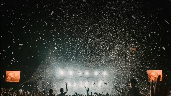 Colorful concert crowd celebrating with confetti at night, vibrant music event, lively atmosphere, music festival, concert, a