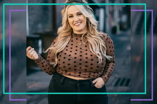 Blonde woman smiling outdoors wearing a sheer brown top with black stars, black high-waisted jeans, and layered gold necklace