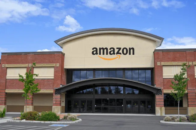 Modern Amazon fulfillment center with a brick facade and large glass entrance, showcasing logistics and e-commerce warehouse