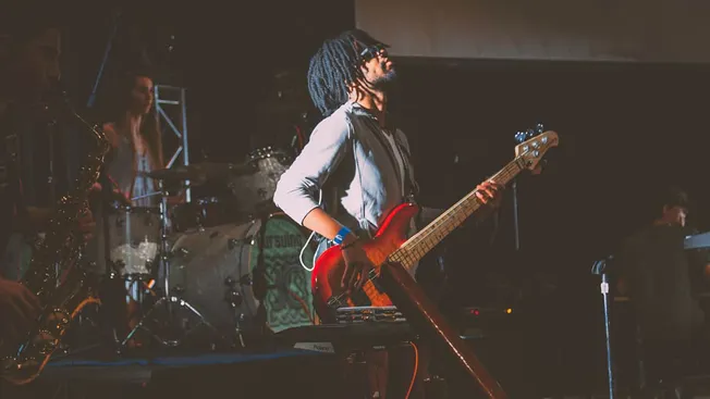 Vibrant live music performance featuring a guitarist with dreadlocks and a keyboardist on stage at a music event.