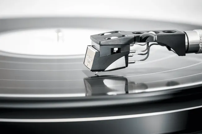 Turntable with tonearm and stylus playing vinyl record, high-quality audio equipment, music production, DJ equipment, analog