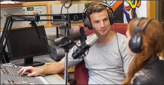 Recording studio with two people speaking into microphones for podcasting or radio broadcasting, using professional audio equ