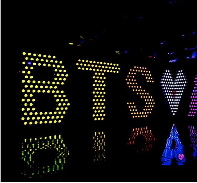 Bright LED lights spell out "BITSH" on a dark background, colorful illuminated sign for music and nightlife venues, vibrant d