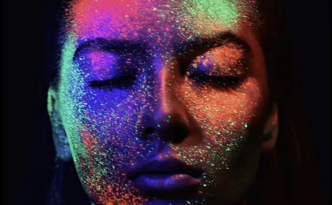 Neon face paint glowing under UV light, vibrant colorful artistic makeup on a woman's face, creative makeup art for night eve
