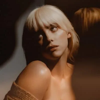 A young woman with blonde hair and a contemplative expression, spotlighted in a dimly lit setting, highlighting modern fashio