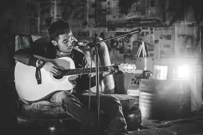Guitarist performing in a cozy, artistic space with immersive lighting and background, capturing a relaxed and creative music