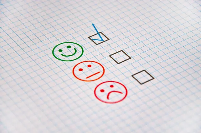 Happy face, sad face, and neutral face drawn on graph paper with checkboxes for customer feedback or satisfaction survey.