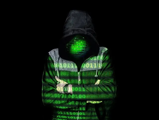 Hacker in a hoodie with a digital green binary code overlay on a black background, representing cyber security threats and di