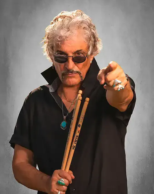 Drummer with sunglasses pointing forward holding drumsticks, music studio background, rock musician style, vintage look, musi