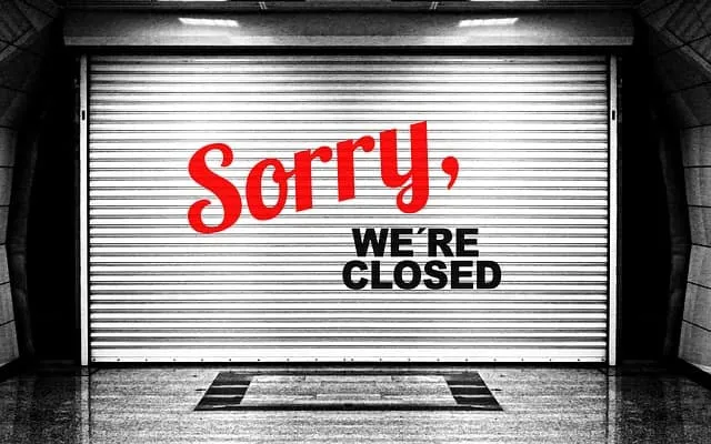 Sorry, we’re closed sign on a metal shutter door in black and white.