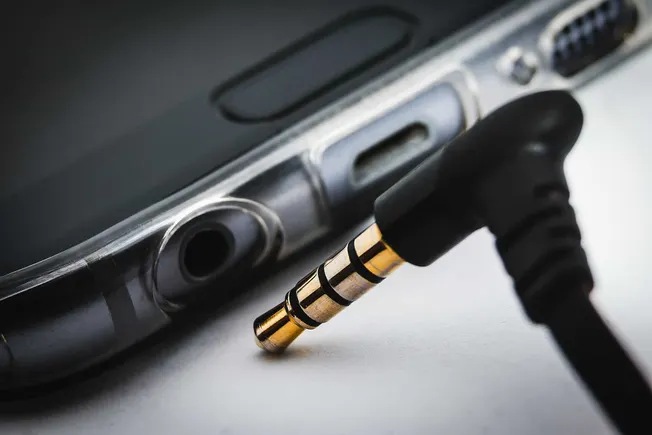 Close-up of a 3.5mm headphone jack plugged into a device, highlighting audio connection technology and portable music accesso