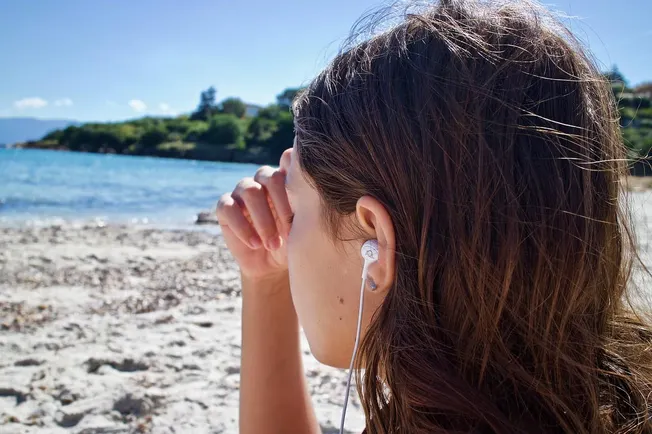 Woman listening to music at the beach with earphones, summer, relaxation, nature, ocean, music, outdoor, vibrant scenery, lei