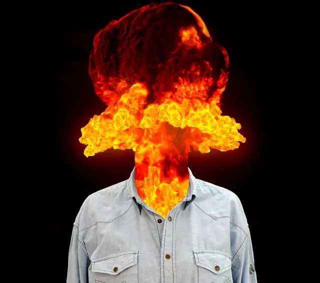 A person with a human body wearing a light gray shirt, but whose head and neck are replaced by a fiery explosion resembling a