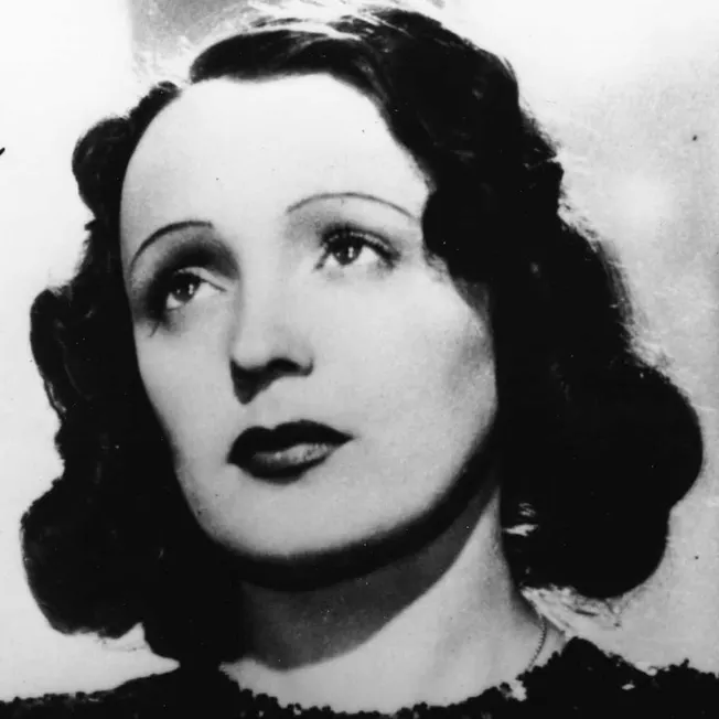 Vintage black and white portrait of a woman with styled wavy hair, classic makeup, and a contemplative expression, exemplifyi