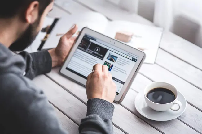 Tablet with online article and coffee on wooden table, digital media consumption, news reading on tablet, casual workspace li