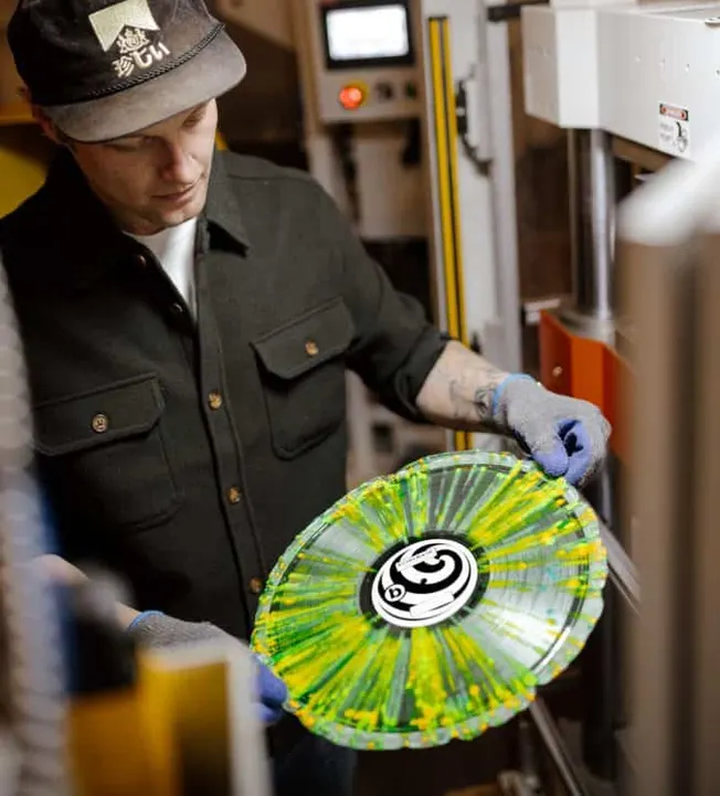 Handblown glass artist creating colorful glass artwork in a studio with industrial equipment.