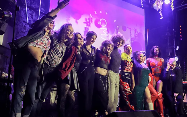 People on stage at a music event with vibrant lighting and diverse fashion styles for a hype music industry promotion.