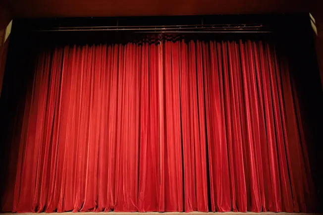 Red theater stage curtain with theater rigging and stage trim.