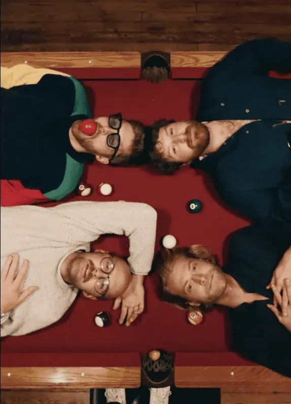 Nostalgic group of friends lying on a billiards table playing pool and having fun, relaxed social gathering, casual entertain